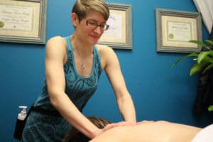 Woman in a blue tank top giving a massage to a client