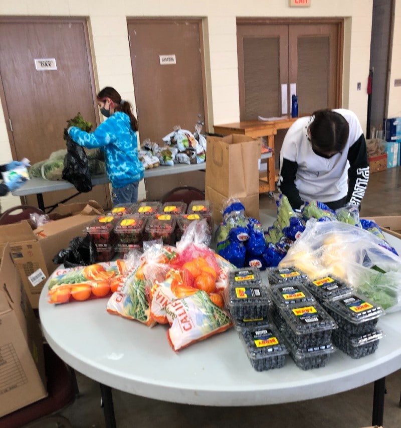 Image of volunteers packing food into bags for delivery. 
