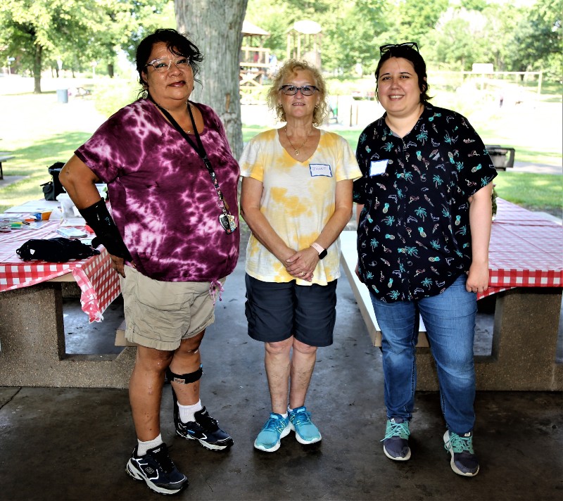3 staff members pose together at an outdoor picnic. 